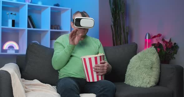 Senior Man Wearing Virtual Reality Glasses and Lift Up His Hand to Selective with VR Screen