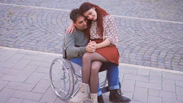 disabled person in love - man with paraplegia holding hands with girlfriend