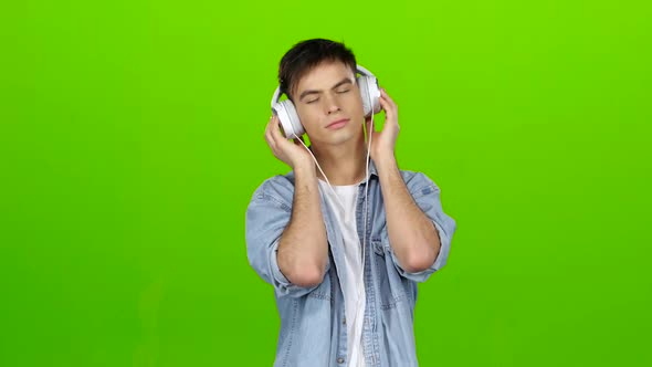 Guy Listens To the Music in the Headphones and Adjusts To the Positive. Green Screen
