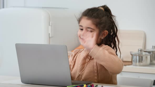 Little Arabic Girl Waving Hello To Laptop In Modern Kitchen