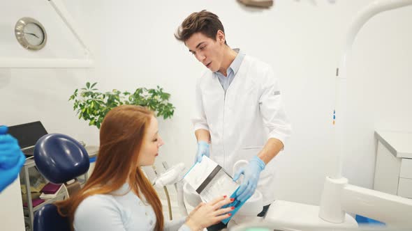 Professional Dentist or Orthodontist Showing Aligners or Kappa for Teeth Alignment to Female Patient