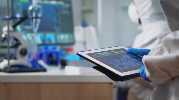 Scientist in Coverall Analyzing Virus Evolution Looking on Digital Tablet