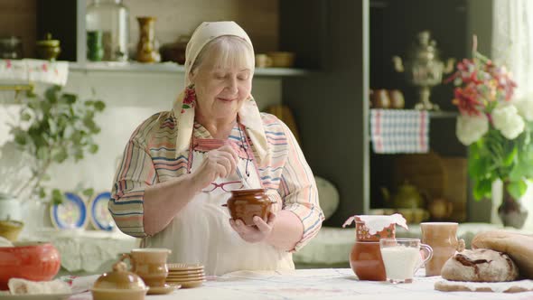 Senior Woman Wearing Headscarf Cooking Sour Cream in Country