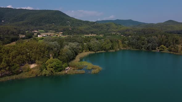 Aerial view over a beautiful landscape with a natural lake surrounded by trees, and a peaceful villa