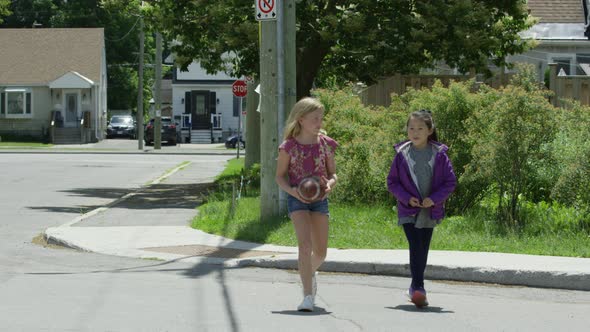 Young girls walking to school carrying a football