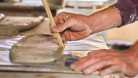 Male potter designing clay with sticks