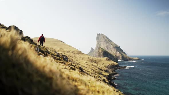 Man in the Cliff, Ocean Waters and Drangarnir Rocks in Faroe Island