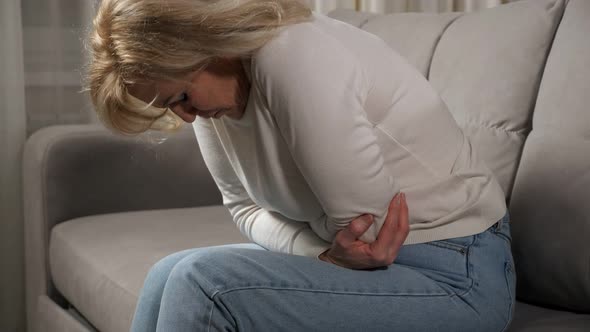 Woman Feels Severe Pain in Joints of Elbows Sitting on Sofa