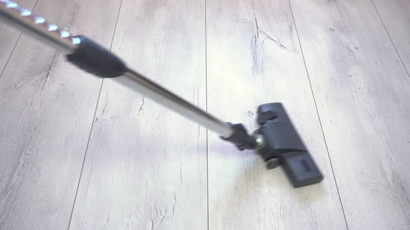 Vacuum Cleaner Brush Removes Dust From Gray Laminated Floor