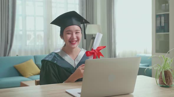 Excited Asian Woman Smiling And Showing Off A University Certificate To Camera