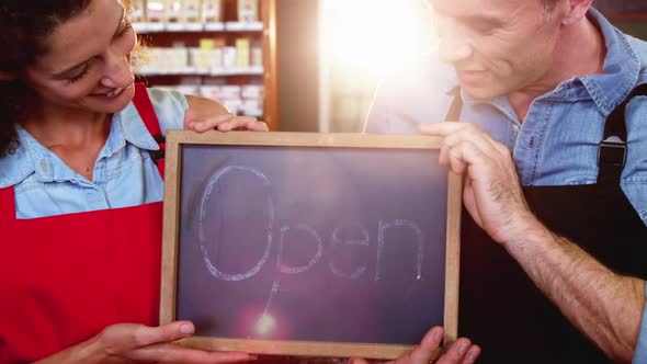 Staff holding a open sign slate in supermarket