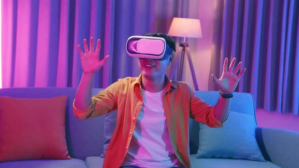 Young Asian Man Explores Virtual Reality At Living Room, Cyan And Magenta Colours