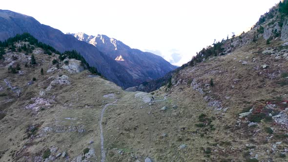 Hikers at Lac d'Espingo ridge in Haute-Garonne, Pyrénées mountains, France, Aerial dolly out reveal