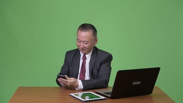 Mature Japanese Businessman Multi-tasking Work