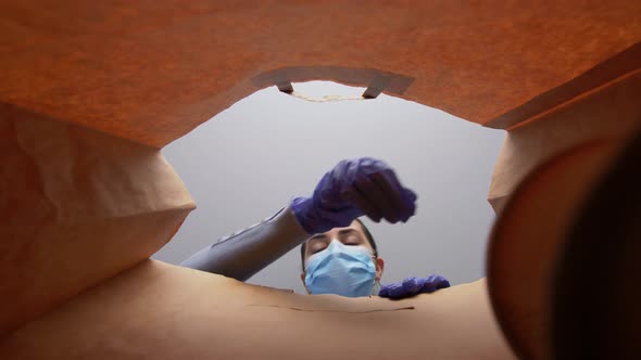 Woman in Gloves and Mask Packing Food in Paper Bag