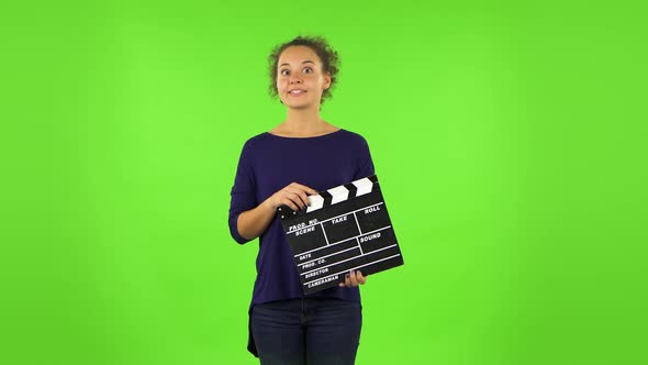 Curly Woman Is Holding a Movie in Her Hands. Green Screen