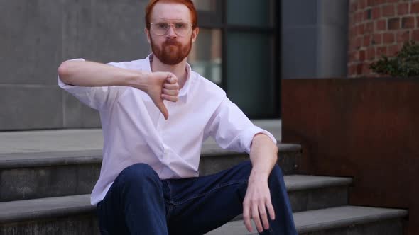 Thumbs Down By Designer Sitting on Office Stairs