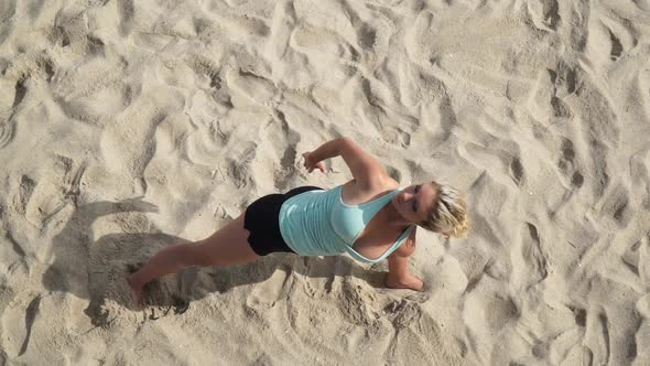 Overhead shot of a young attractive woman doing yoga on the beach