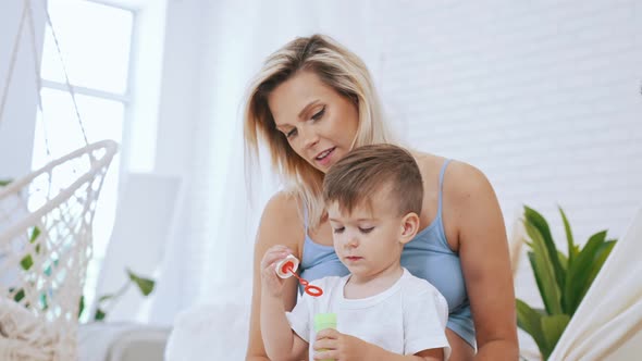 Little Boy Making Soap Bubles with Mother at Home Medium Closeup Mother Concept