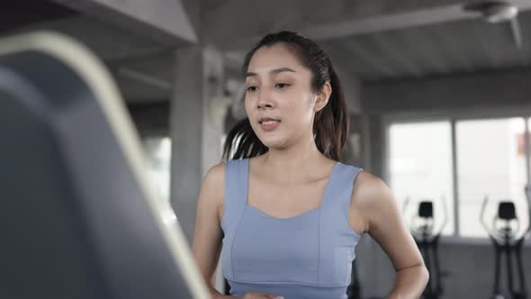 4K Portrait of Asian sportswoman in sportswear jogging workout exercise on treadmill at fitness gym.