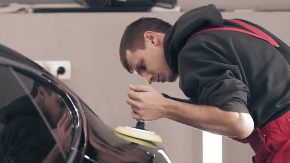 Male Worker at Autocenter Polishing Black New Car with Precise Accuracy