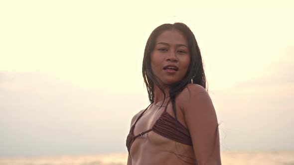 Beautiful Young Woman Looking At Camera On Beach At Sunset