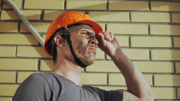 Dirty Building Worker on Background Brick Wall