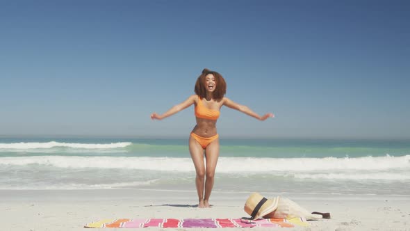 African american woman jumping at beach