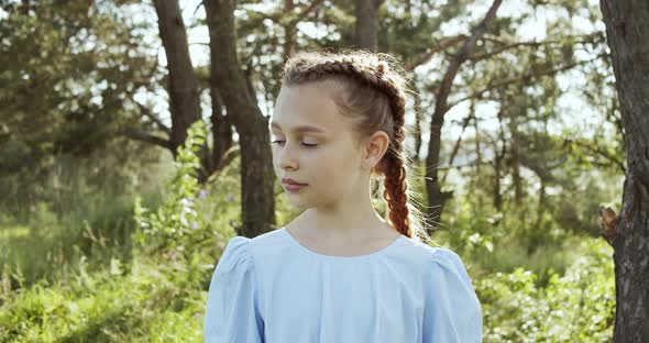 Attractive European Blonde Teen Girl with Natural Makeup Looks Into the Camera in Nature on a Sunny