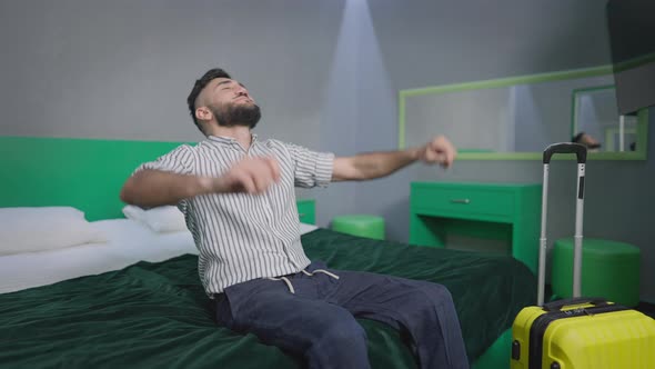 Joyful Carefree Tourist Falling Back on Comfortable Bed in Hotel Room