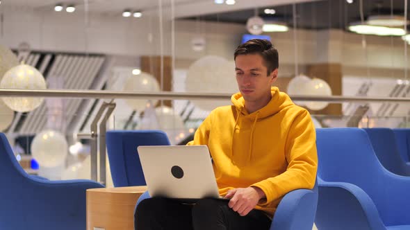 Young Confident Busy Man Working on a Laptop While Sitting in a Cafe