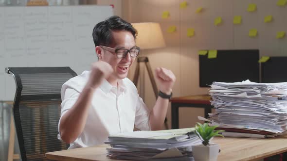 Happy Asian Man Celebrating Finishing Working With Documents At The Office