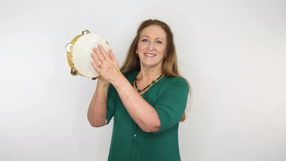 A teacher presents a tambourine in her music class to students.