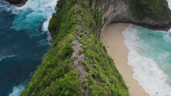 Man hiking down sharp cliff with idyllic beach in background, Aerial, Bali