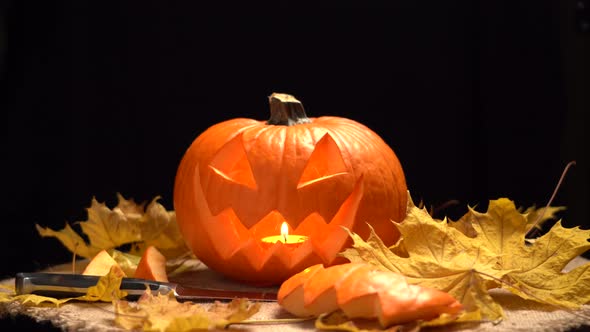 Jack O Lantern Halloween Pumpkin with Candle Inside on Yellow Leaves