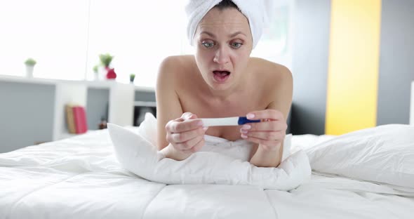 Joyful Woman Looking at Pregnancy Test While Lying in Bed