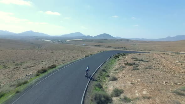 Aerial shot of a young athletic woman cycling downhill on a road bike in the mountains in Spain. Sho