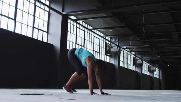 African american woman doing jumping exercises in an empty urban building