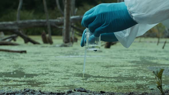 Process of Taking Water Analysis From Swamp Using Flask and Pipette Wearing Protective Suit and