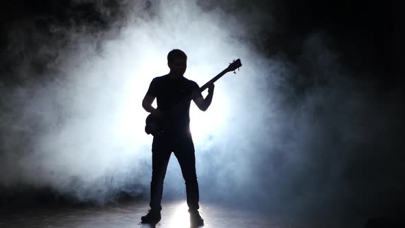 Musician Jump While Playing the Bass Guitar, Dark with Smoke