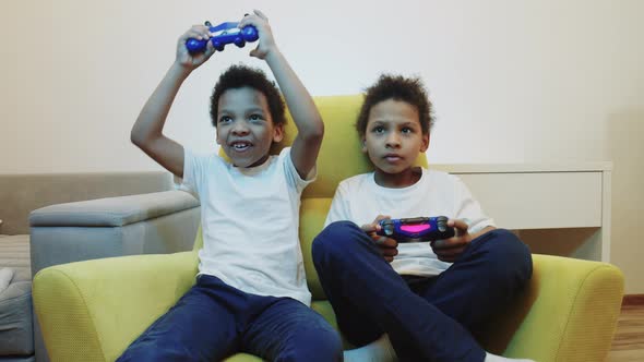 Two Little Black Boys Brothers Playing a Game Using Joysticks