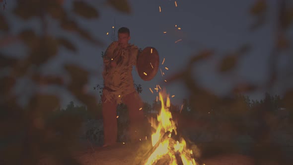 A Shaman with a Drum Jumps in Around the Fire in Clothes for the Ceremony