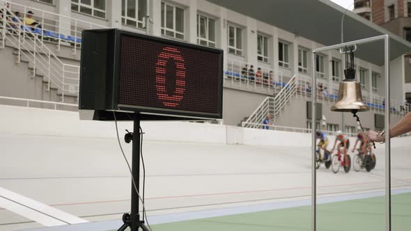 Cycling referee rings bell on velodrome. Lap screen on cycling track.