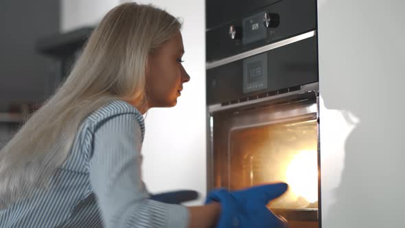 Close Up of Happy Young Woman Removing Hot Croissants From Oven at Home