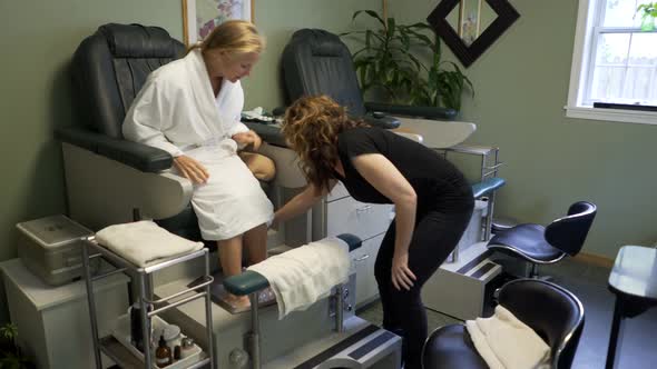 Mature woman takes feet out of bath and puts them on towel preparing for her pedicure. Steadicam sho