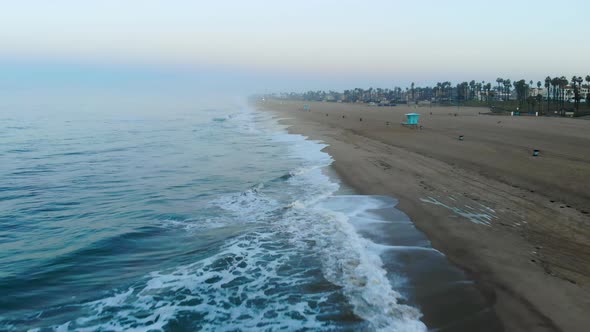 A 4k  ariel view moving down the foggy coast in Huntington Beach California Surf City USA at sunrise