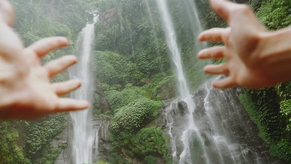 Amazing big waterfall in jungles. Traveller show it with hands. Asian nature.