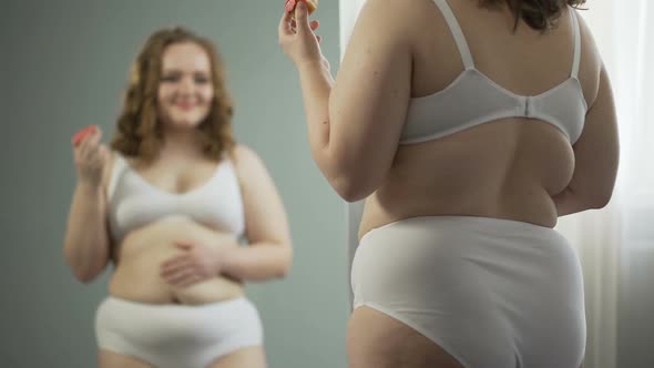 Fat Lady in Underwear Looking at Her Mirror Reflection and Enjoying Sweet Donut