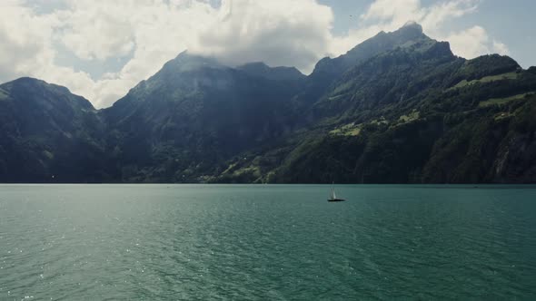 A Sailboat Floats on a Picturesque Lake at the Foot of the Alpine Mountains