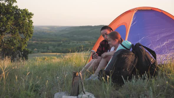 Girl with Phone While Sitting Inside Tent with Her Mother. Mother and Daughter Resting in a Tent